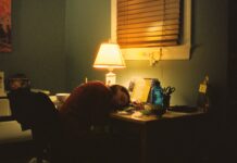 만성피로, 단순한 피로가 아닌 신호… 원인과 극복 방법은? a person sitting at a desk in front of a lamp