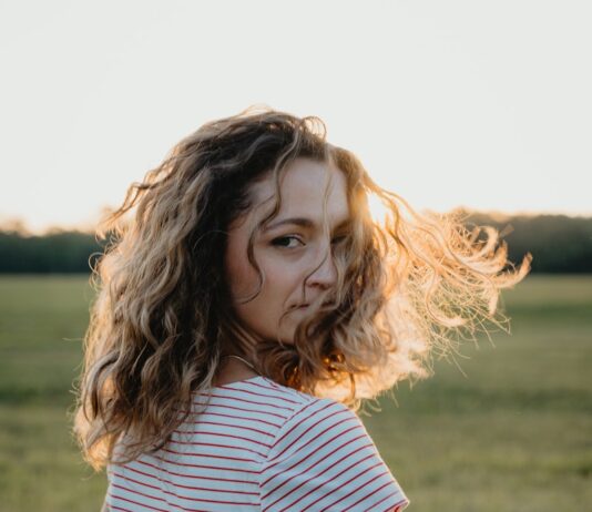 내 안의 건강 시계를 되돌리다: 2025년 최신 웰니스 트렌드 총정리 Woman with curly hair in a field at sunset