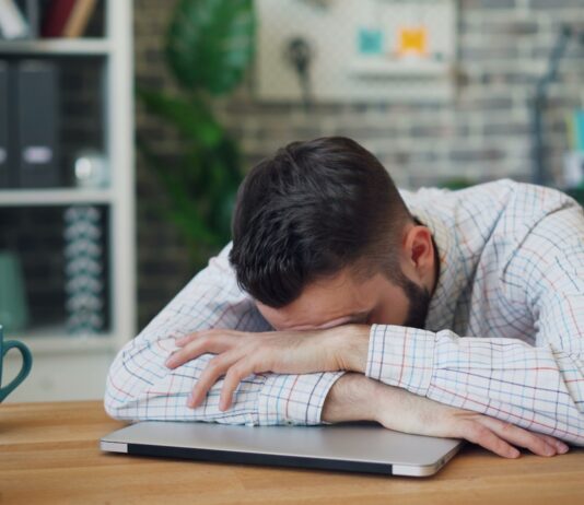 만성피로, 단순한 휴식으로 해결 안된다…새로운 접근법 필요 a man sitting at a desk with his head in his hands