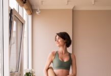 “필라테스 열풍, 집에서도 건강하게 즐기는 실생활 루틴” a woman in a green sports bra top and leggings holding a yoga mat