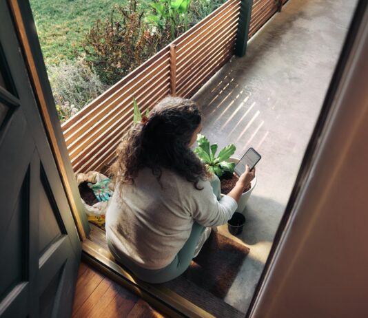 만성피로, 작은 습관 변화로 이겨내기… 한국인 맞춤 활력 찾기 전략 Woman sitting on balcony with smartphone